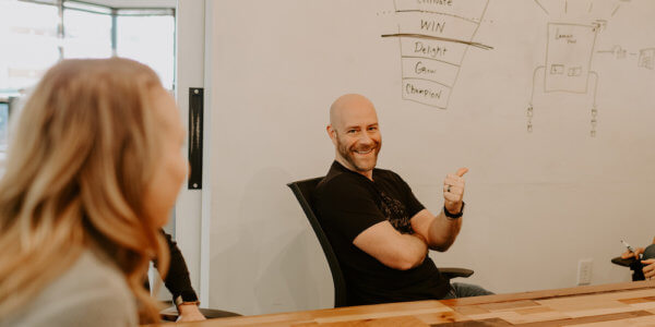 Jason in front of whiteboard explaining how for is greater than to in marketing