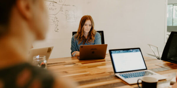 Chelsea sitting at a table on her computer after setting and measuring quarterly goals with a client