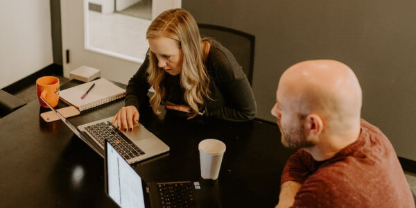 Kate and Jason looking at laptops and discussing how improving your ltv can help your business growth