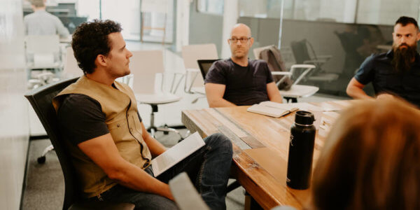 Kraig, Jason, Benj and team sit in room for quarterly meeting to discuss hitting yearly goals