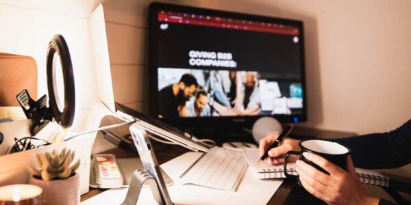 Home office set up with computer and person holding coffee cup