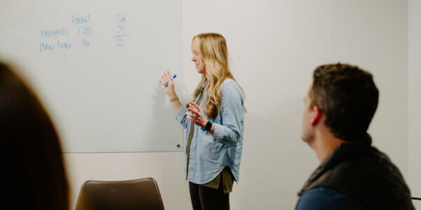 Kate looking at a white board while holding a white board marker and talking through 2022 with the team