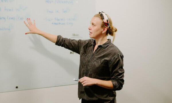 Jordan-Ann, Syrup team member, pointing at a white board while talking to her team about client retention strategies