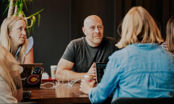 Jason and Kate sitting at a table talking to a woman about sales mindset heading into Q4
