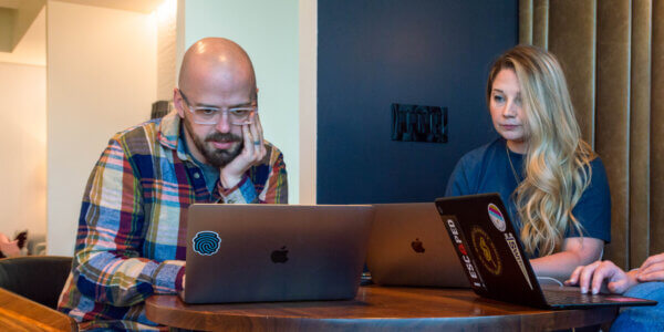 Lars and Paiton, two Syrup team members, sitting at a table looking at their laptops discussing hubspot