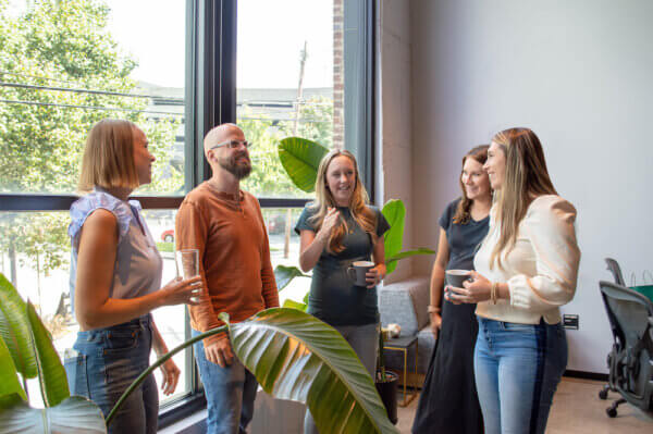 Group of Syrup employees standing around the office talking about creating brand advocates