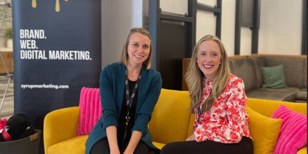 Two ladies sitting on a gold couch at a B2B event