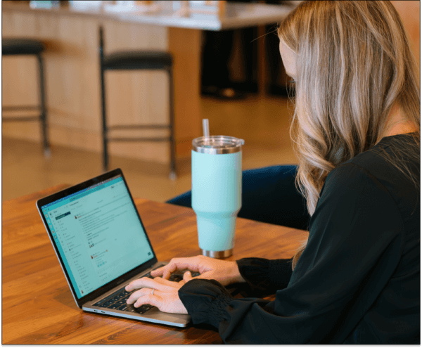 Woman sitting at table typing on her laptop about remote team creativity
