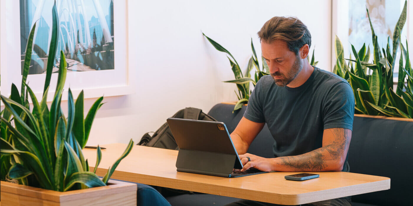Benj sitting at table looking at his laptop thinking about consumer skepticism