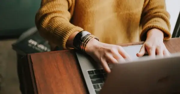 Woman in yellow sweater typing on computer