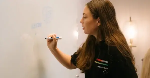 Brooke writing on whiteboard brainstorming rebrand
