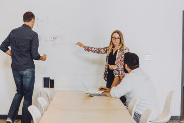 Woman pointing at whiteboard while proving marketing roi to leadership watching on