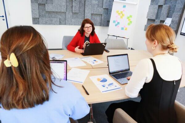 Two women sitting on one side of a table presenting marketing ROI to another woman across from them