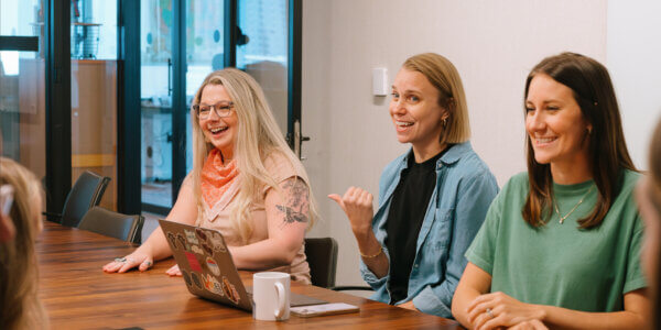 Group of women around table with laptop talking through AI-first search