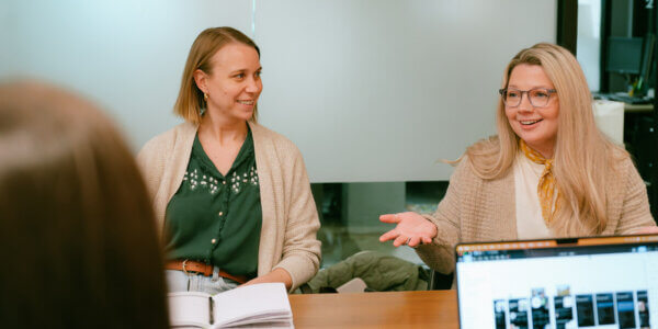 Two women sitting at conference table smiling and discussing ai visibility audit