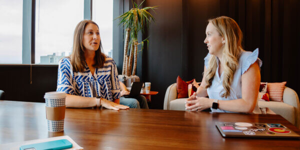 Kate and Morgan sitting at a table discussing cutting marketing R&D