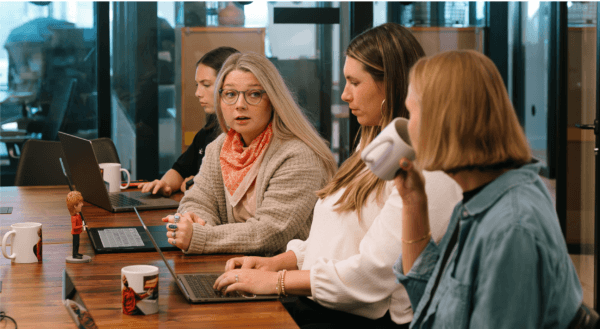Two women sitting at a table smiling and discussing CRM for business