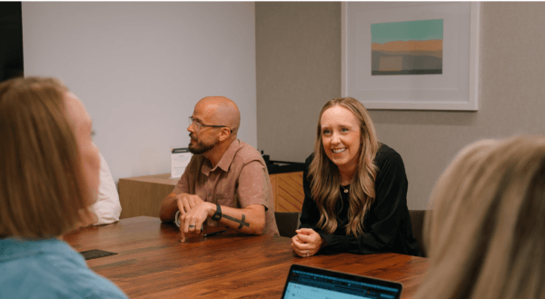 Group of people sitting at table discussing partner-led growth