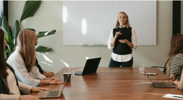 Jordan-Ann standing in front of team at a table discussing b2b marketing strategy